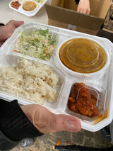 食料配給で配布された温かいインドカレー弁当と缶詰のあんパン